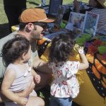 Man and children examine pollinator game at UCCE Master Gardeners Plantpalooza booth