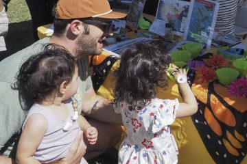 Man and children examine pollinator game at UCCE Master Gardeners Plantpalooza booth